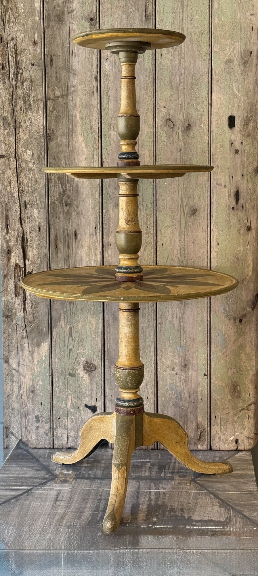 A Victorian three-tier wooden pedestal table with a painted finish, turned central stem, starburst motif, and tripod feet. View X