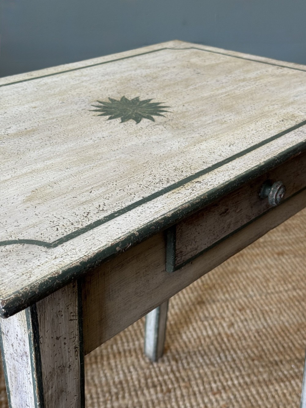 An off-white painted French provincial lamp table with dark trimmed borders, a star motif top, tapered legs, and a single drawer. View II