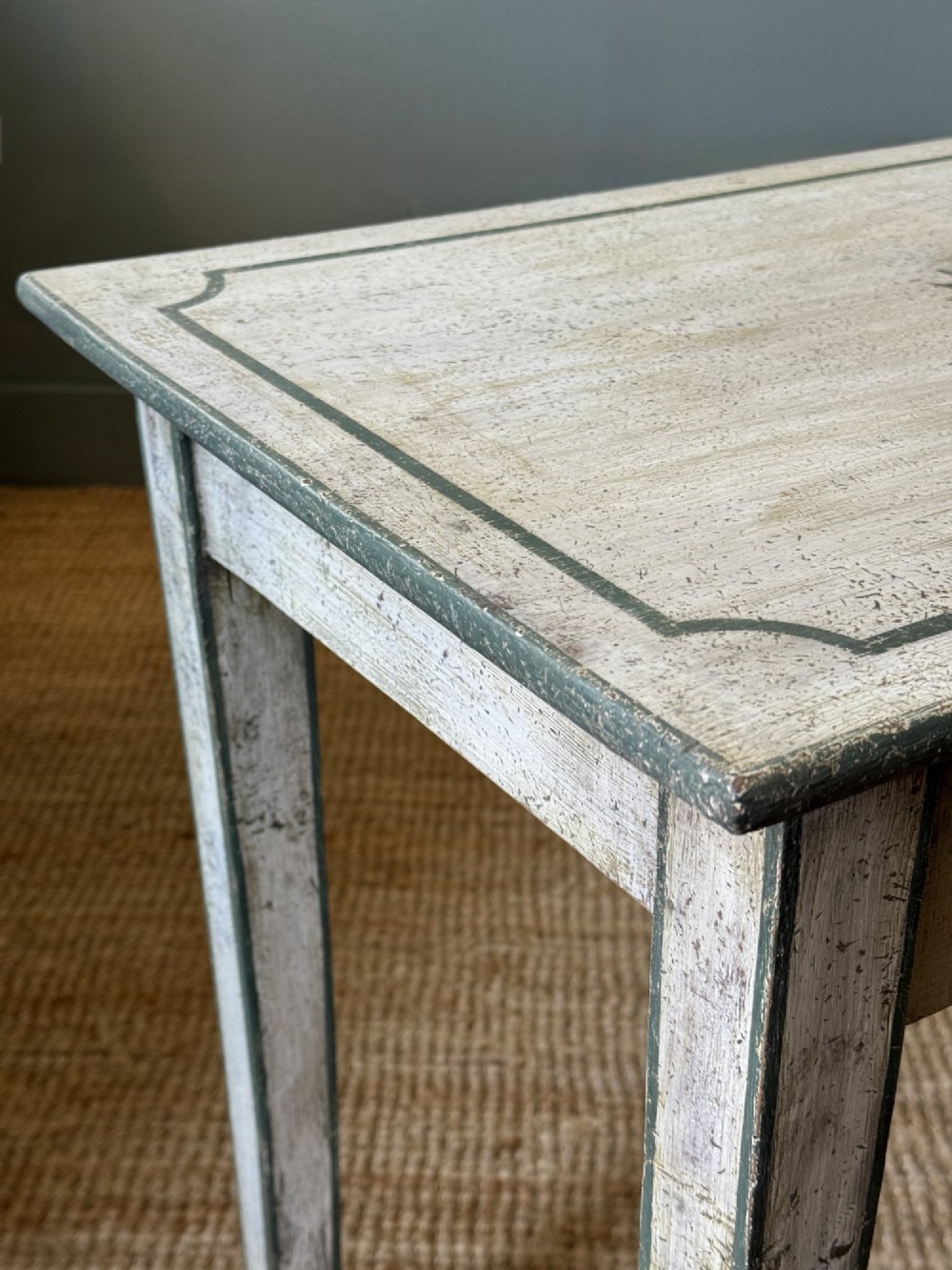 An off-white painted French provincial lamp table with dark trimmed borders, a star motif top, tapered legs, and a single drawer. View III