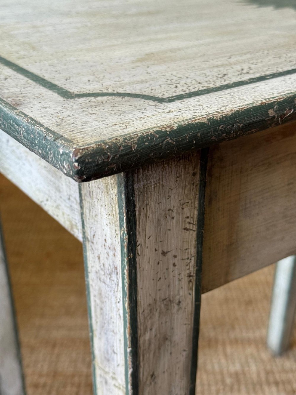 An off-white painted French provincial lamp table with dark trimmed borders, a star motif top, tapered legs, and a single drawer. View VI