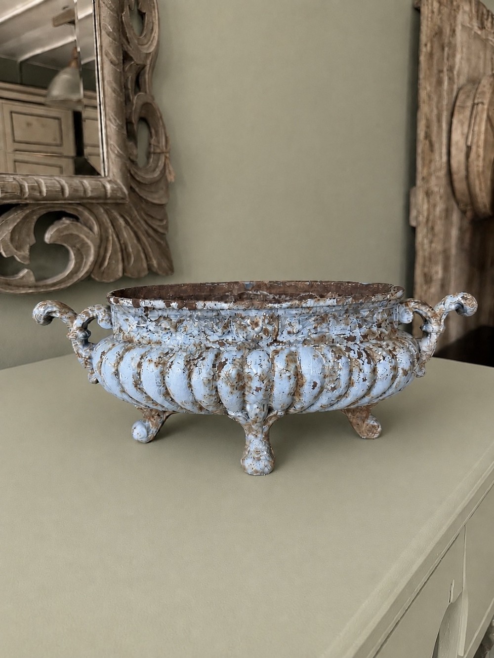 A 19th-century French cast iron jardiniere with fluted details, twin scroll handles, and a distressed pale blue painted surface finish.