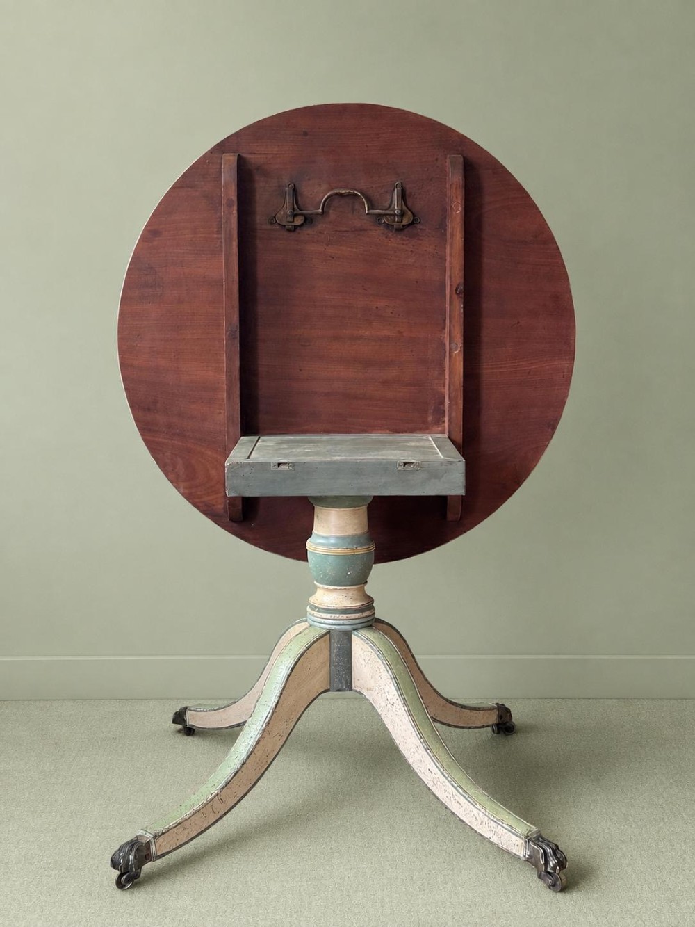 A circular Victorian tilt-top table featuring hand-painted geometric and botanical foliage patterns in green and yellow on a cream ground, resting on a tripod base with brass claw feet. View IV