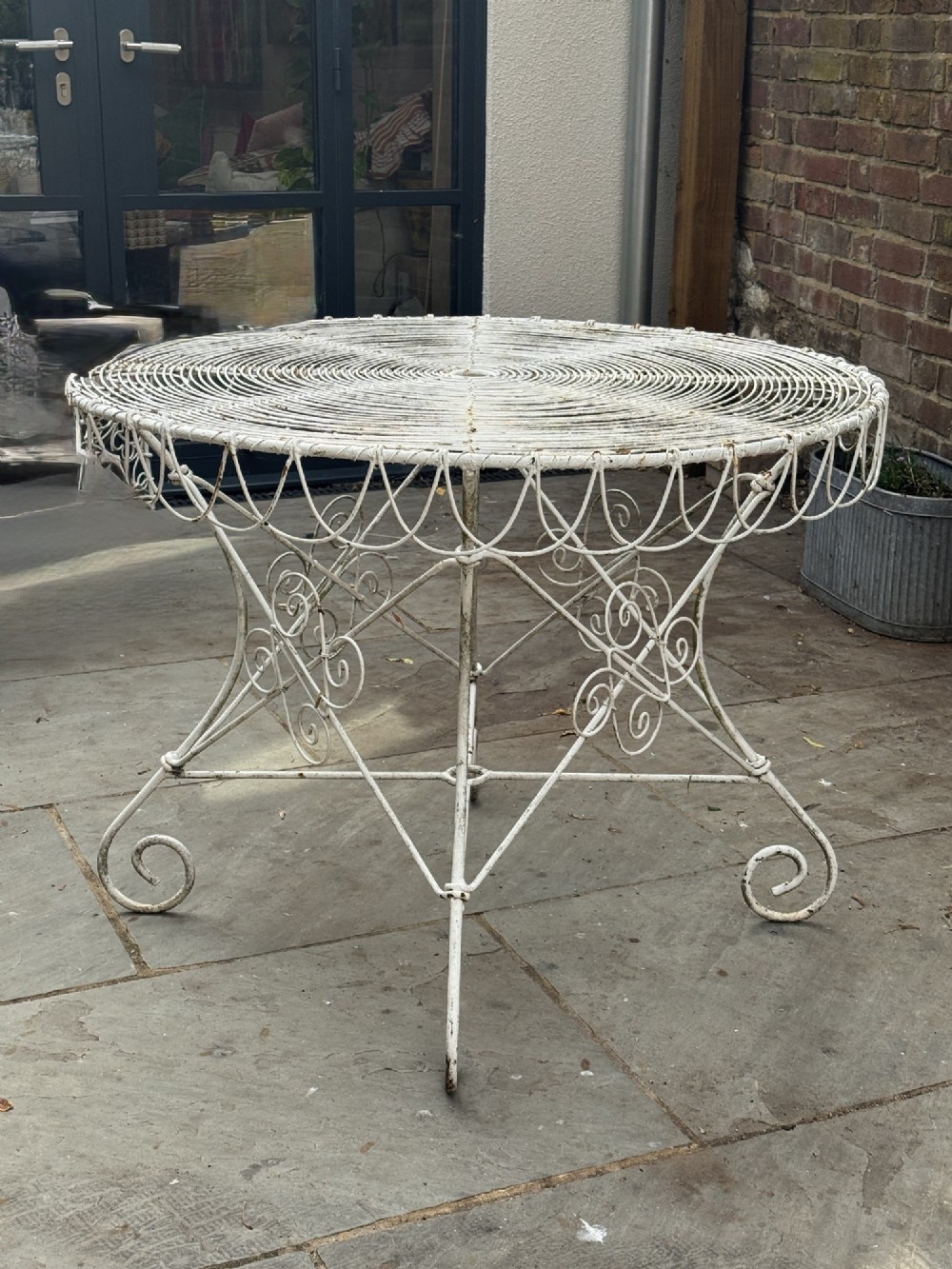 A white wrought iron garden set featuring a circular wirework table and four matching armchairs with pink and white striped cushions. View II