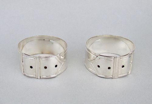 fig 2. A pair of Victorian silver-plated napkin rings designed to resemble buckled belts, resting inside a velvet-lined presentation box.