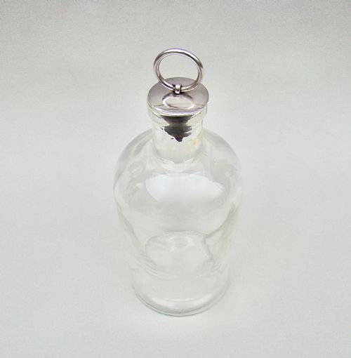 fig 1. A clear glass cologne bottle with acid-etched floral patterns and a metal-capped cork stopper topped with a silver-coloured ring pull.