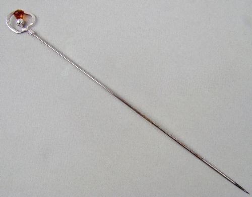 fig 1. An antique silver hat pin featuring a Scottish thistle design set with an amber glass top, stamped with C.H maker marks.