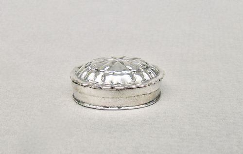 fig 2. A small round Dutch silver pill box featuring a scalloped rim and an embossed floral repousse lid.