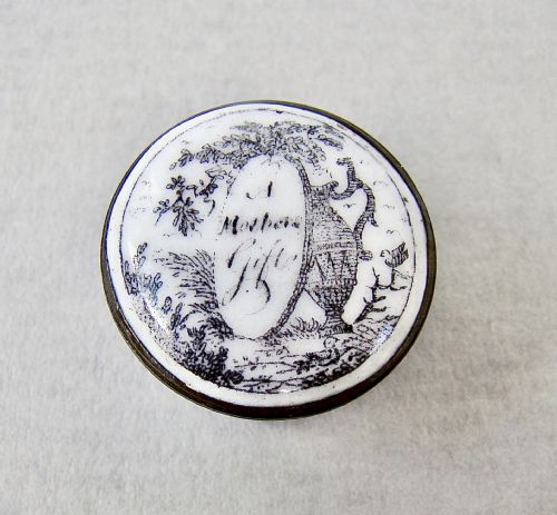 fig 2. A small circular Georgian enamel patch box featuring a light blue base and a hinged white lid with a black transfer-printed urn image and the text A Mothers Gift.