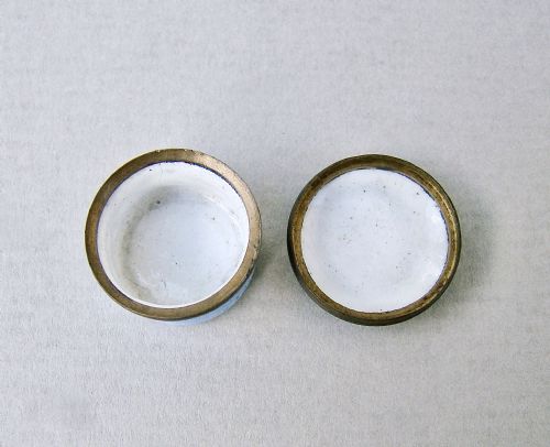 fig 4. A small circular Georgian enamel patch box featuring a light blue base and a hinged white lid with a black transfer-printed urn image and the text A Mothers Gift.