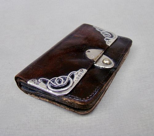 fig 1. A late Victorian dark brown leather purse featuring scroll-patterned silver corner mounts with hallmarks and an oval metal central clasp.