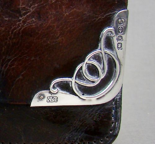 fig 3. A late Victorian dark brown leather purse featuring scroll-patterned silver corner mounts with hallmarks and an oval metal central clasp.