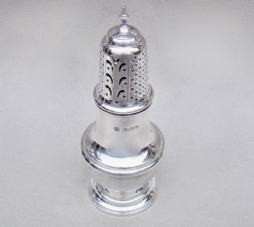 fig 1. A solid silver sugar caster featuring a baluster body, hallmarks on the neck, a pierced dome lid, and a turned finial top.
