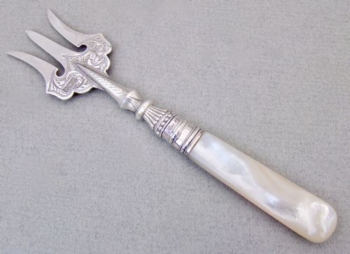fig 1. An Edwardian sterling silver three-tined bread fork with an engraved blade and mother of pearl handle inside an open fitted case.