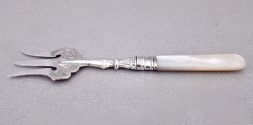 fig 2. An Edwardian sterling silver three-tined bread fork with an engraved blade and mother of pearl handle inside an open fitted case.