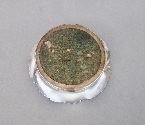 fig 2. A circular William IV Old Sheffield Plate wine coaster featuring a turned wooden insert, central silver boss, and a chased border decorated with grapevines and leaves.