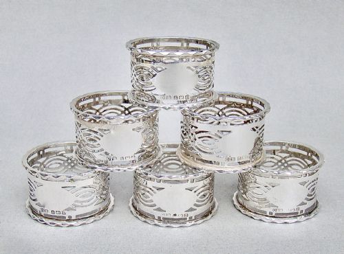fig 1. A cased set of six sterling silver napkin rings with pierced geometric decoration, presented inside a dark velvet and silk lined box.
