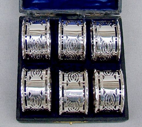 fig 2. A cased set of six sterling silver napkin rings with pierced geometric decoration, presented inside a dark velvet and silk lined box.