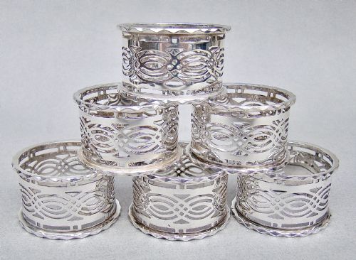 fig 3. A cased set of six sterling silver napkin rings with pierced geometric decoration, presented inside a dark velvet and silk lined box.