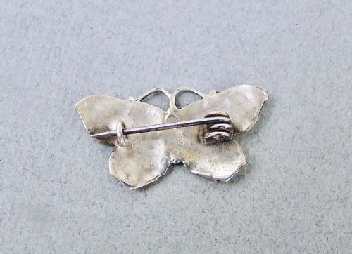 fig 1. An Art Deco silver butterfly brooch featuring light green translucent enamel wings and a dark blue enamel body.