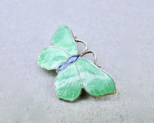 fig 2. An Art Deco silver butterfly brooch featuring light green translucent enamel wings and a dark blue enamel body.