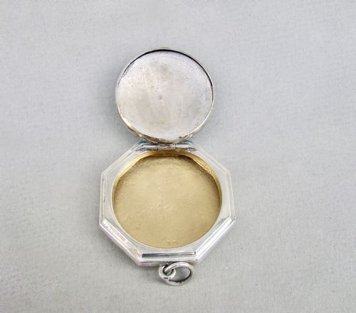 fig 3. An octagonal sterling silver Art Deco compact featuring a central circular panel of bright turquoise blue guilloche enamel with a suspension loop.