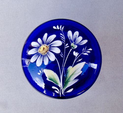 fig 2. A deep cobalt blue glass dressing table jar featuring hand-painted white daisy enamel decoration and a hinged metal rim.