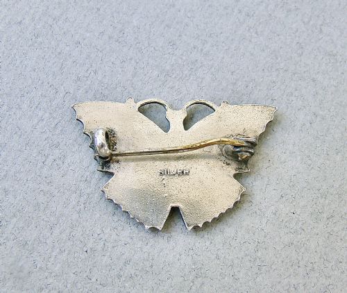 fig 1. A 1930s sterling silver butterfly brooch featuring engine-turned guilloche enamel in shades of burnt orange and pale green with black spot details.