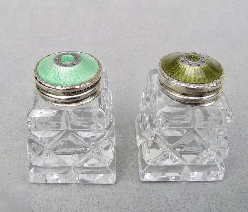 fig 2. A pair of Art Deco cut glass salt shakers featuring green guilloche enamel and silver tops, shown in front of their fitted presentation box.