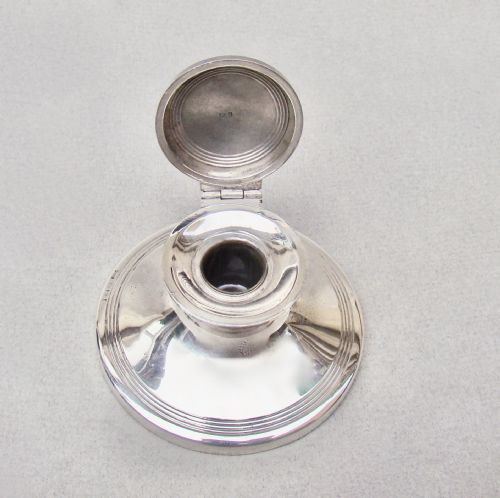 fig 3. A circular Edwardian sterling silver capstan inkwell featuring a hinged lid inset with a floral guilloche enamel medallion.