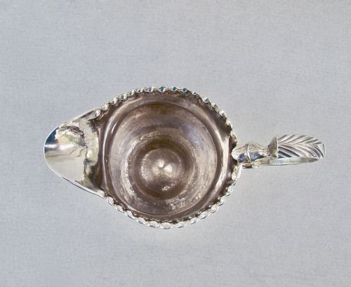 fig 3. A Georgian sterling silver cream jug featuring a baluster shape, beaded rim, pedestal base, and engraved initials, assayed in London in 1777.