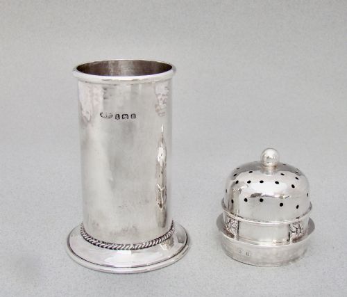 fig 2. A cylindrical sterling silver sugar caster featuring a domed perforated lid, floral band motif, rope twist base, and visible English hallmarks.
