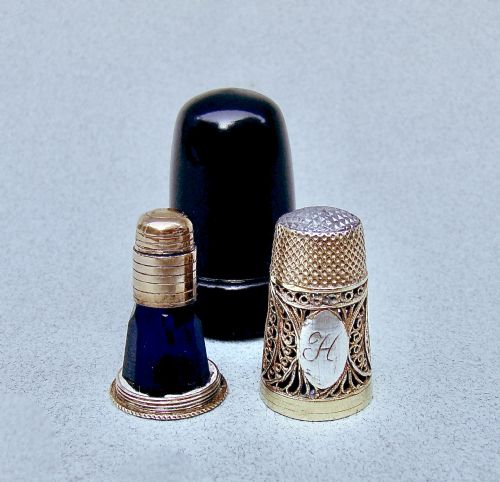 fig 1. A Georgian silver filigree thimble set featuring an engraved monogram, a cobalt blue glass scent bottle insert, a silver cap, and a dark fitted outer case.