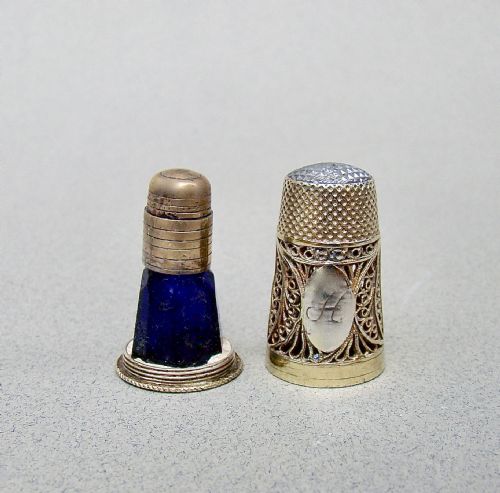 fig 2. A Georgian silver filigree thimble set featuring an engraved monogram, a cobalt blue glass scent bottle insert, a silver cap, and a dark fitted outer case.