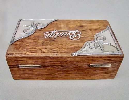 fig 2. An Edwardian oak box featuring sterling silver ribbon corner mounts and a silver script word reading Bridge on the lid.