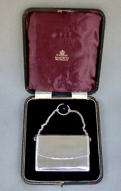 fig 1. An Edwardian sterling silver card case designed in the shape of an envelope with a suspension chain, resting inside a velvet-lined fitted box.