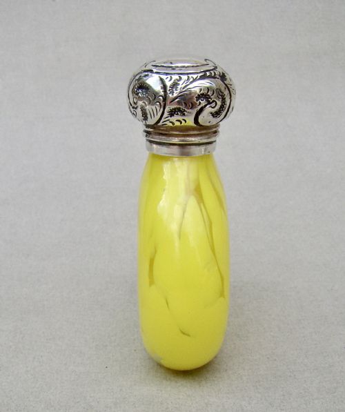 fig 1. A globular yellow splatter glass scent bottle featuring a floral embossed sterling silver cap and hallmarked collar.