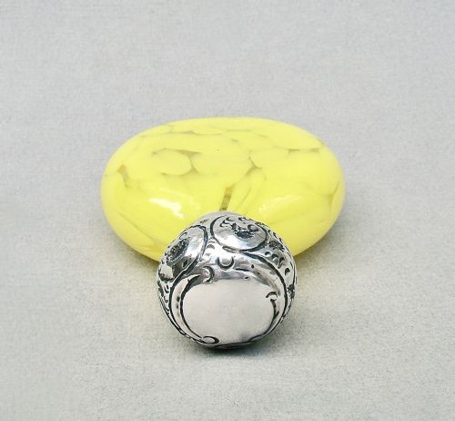 fig 2. A globular yellow splatter glass scent bottle featuring a floral embossed sterling silver cap and hallmarked collar.