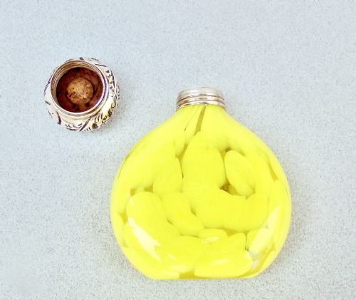 fig 3. A globular yellow splatter glass scent bottle featuring a floral embossed sterling silver cap and hallmarked collar.
