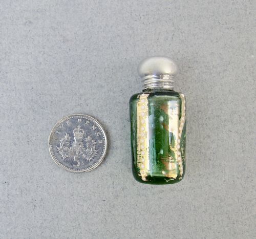 fig 2. A miniature green glass scent bottle featuring painted gilt and enamel dot decoration, topped with a rounded silver screw cap stamped with SILVER.
