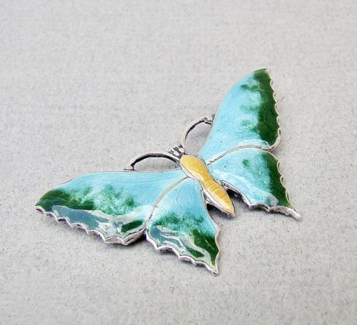 fig 1. A Scandinavian sterling silver butterfly brooch featuring light blue and green guilloche enamel wings with a yellow body.