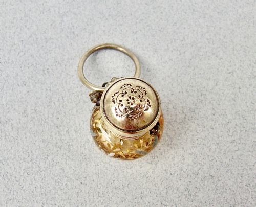 fig 1. A late 19th-century amber glass chatelaine scent bottle decorated with gilded floral enamel details and a metal screw top with attachment rings.