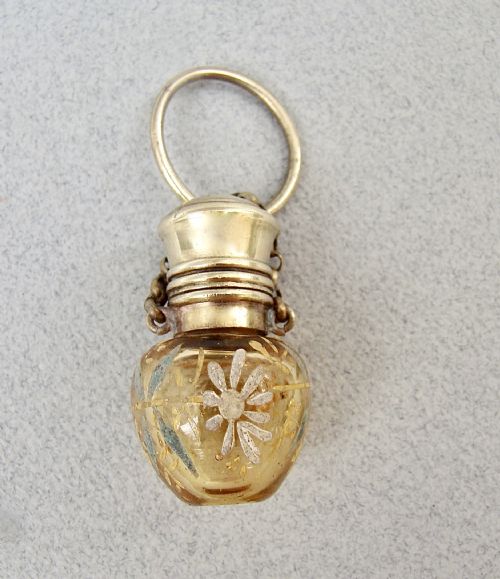 fig 2. A late 19th-century amber glass chatelaine scent bottle decorated with gilded floral enamel details and a metal screw top with attachment rings.