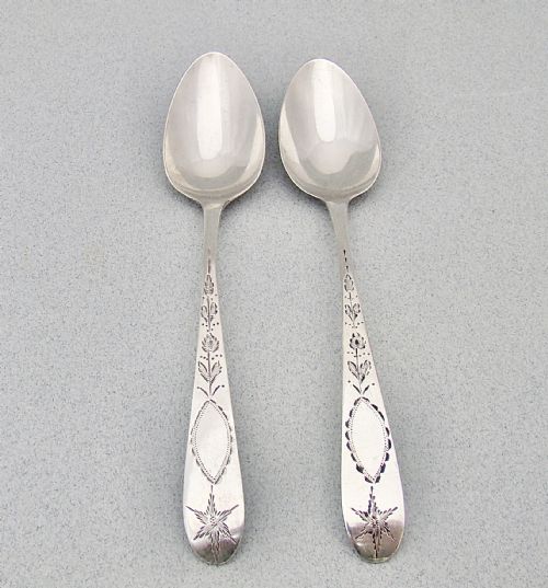 fig 1. A pair of Georgian Irish sterling silver dessert spoons featuring bright-cut engraved stems with starburst and floral detailing.