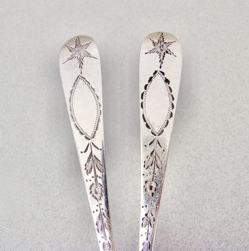 fig 3. A pair of Georgian Irish sterling silver dessert spoons featuring bright-cut engraved stems with starburst and floral detailing.