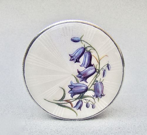 fig 1. A circular Edwardian sterling silver trinket box with a white sunburst guilloche enamel lid decorated with hand-painted purple harebell flowers.