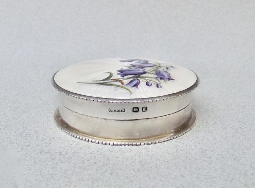 fig 2. A circular Edwardian sterling silver trinket box with a white sunburst guilloche enamel lid decorated with hand-painted purple harebell flowers.