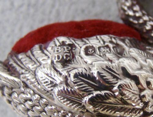 fig 3. An Edwardian sterling silver swan pin cushion featuring chased feather details, a red glass eye, and a red velvet cushion insert.