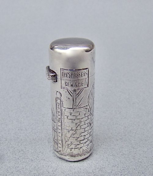 fig 1. A cylindrical Victorian sterling silver scent bottle decorated with an engraved illustration of a child on a brick wall near a milestone.