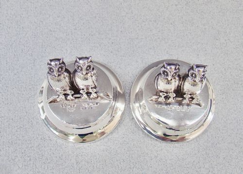 fig 2. A pair of Edwardian sterling silver owl-form menu holders positioned inside a fitted black presentation case lined with blue velvet and beige silk.