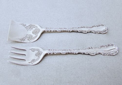 fig 1. A cased set of two late Victorian sterling silver sardine servers featuring engraved scroll decorations resting inside an open fitted presentation box.